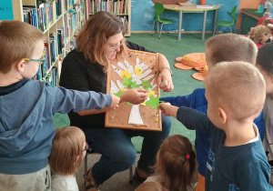 Dzieci przyczepiają do planszy z drzewem kolorowe liście