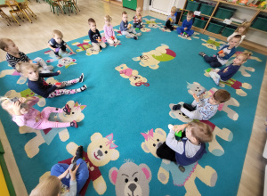 Dzieci siedzą w kole na dywanie z klockami w rękach