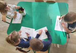 Dzieci wykonują pracę plastyczną przy stoliku