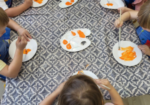Dzieci kolorują papierowe talerzyki na pomarańczowo