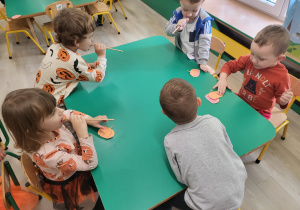 Dzieci wykonują ćwiczenie-dmuchają na dynie
