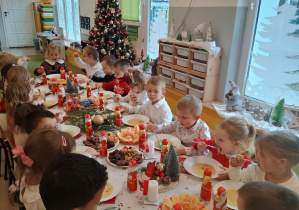 Dzieci spożywają świąteczny obiad przy dźwiękach kolęd