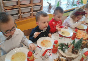Dzieci spożywają świąteczny obiad przy dźwiękach kolęd