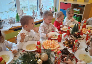 Dzieci spożywają świąteczny obiad przy dźwiękach kolęd