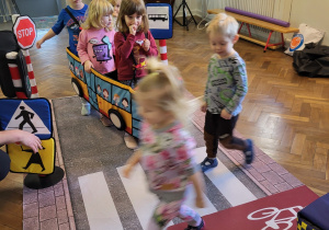 Dzieci w strojach samochodów chodzą po ulicznej macie