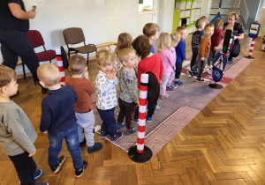 Dzieci stoją w kolejce do strażniczki miejskiej