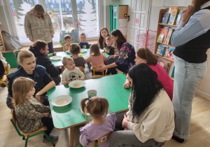 Dzieci i rodzice siedzą przy stolikach, na których stoją talerze z wodą z pieprzem