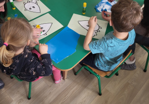 Dzieci z rodzicami wykonują pracę plastyczną przy stolikach