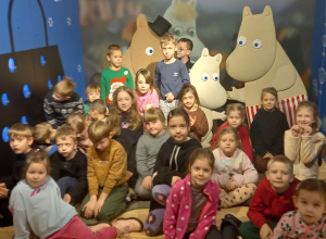 Dzieci pozują do zdjęcia na tle Muminków