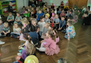 Dzieci siedzą na sali gimnastycznej