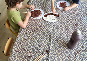 Dzieci malują na brązowo papierowe pączki