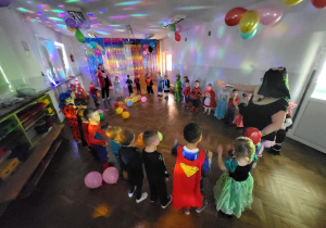Dzieci w przebraniach stoją w kole i tańczą