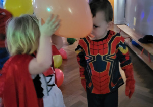 Chłopiec i dziewczynka w przebraniach trzymają balona czołami