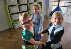 Dziewczynki w przebraniach trzymają się za ręce w kole