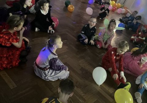 Dzieci siedzą i bawią się w grupach