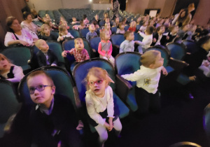Dzieci siedzą na widowni teatru, rozglądają się