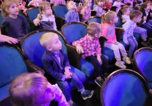 Dzieci siedzą na widowni teatru, rozglądają się