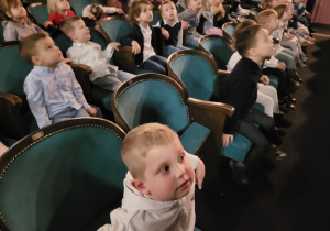 Dzieci siedzą na widowni teatru, rozglądają się