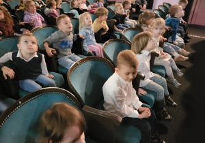 Dzieci siedzą na widowni teatru, rozglądają się