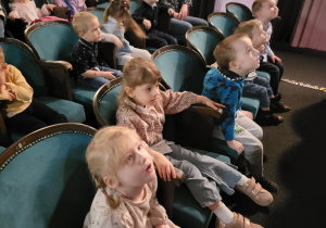 Dzieci siedzą na widowni teatru, rozglądają się