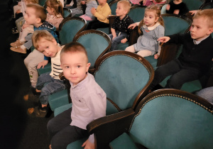 Dzieci siedzą na widowni teatru, rozglądają się