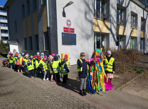Przedszkolaki czekają w parach na wyjście na spacer, dwie dziewczynki trzymają Marzannę