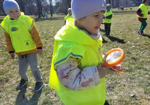 Dzieci szukają owadów, dziewczynka trzyma lupę