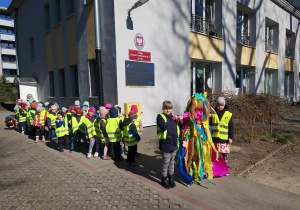 Przedszkolaki czekają w parach na wyjście na spacer, dwie dziewczynki trzymają Marzannę