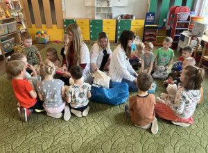 Dzieci siedzą na dywanie ze studentkami UM