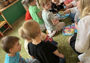 Dzieci siedzą na dywanie i leczą swoje pluszowe misie