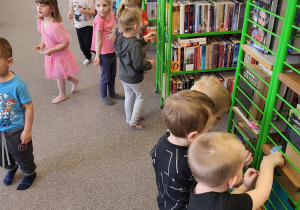 Dzieci szukają jajeczek na półkach z książkami
