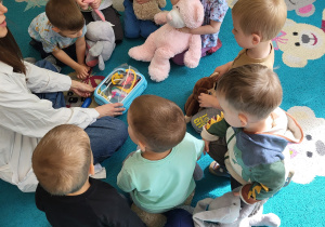 Dzieci trzymają misie i zgłaszają się do odpowiedzi