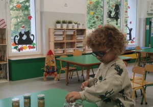 Chłopiec wkłada aluminiowe kulki do słoika