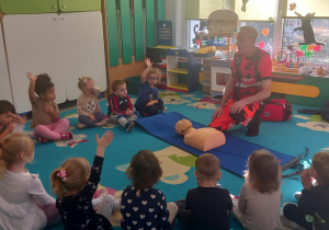 Dzieci siedzą w kole z ratownikiem