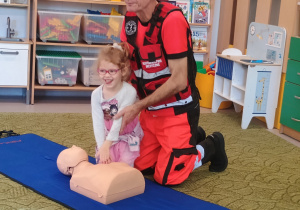 Dziewczynka uciska klatkę piersiową na fantomie