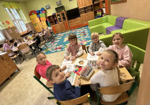 Dzieci siedzą przy stoliku i kolorują obraazek