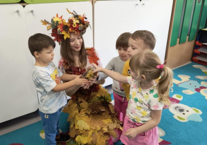 Dzieci podziwiają i dotykają jesienne drzewo w słoiku, które zrobiły razem z Panią Jesień