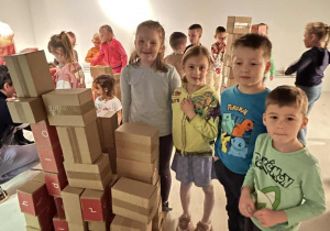 Dzieci pokazują zbudowaną z pudełek fabrykę
