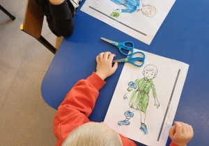 Dzieci wykonują pracę plastyczną - ubierają papierowe kobiety