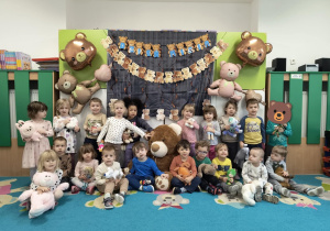 Dzieci pozują do zdjęcia grupowego z pluszakami