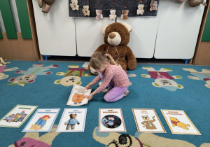 Dziewczynka układa ilustracje przedstawiające różne postacie misiów z bajek