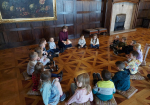 Dzieci siedzą w kole w sali balowej