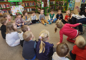 Dzieci siedzą w kole, patrzą na panią bibliotekarkę