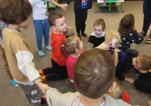 Część dzieci stoi w kole, część dzieci kuca w środku koła