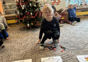 Dziewczynka układa guziki na choince