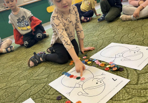 Dziewczynka wybiera guziki pasujące do ilustracji