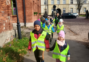 Dzieci idą parami przy kamienicach