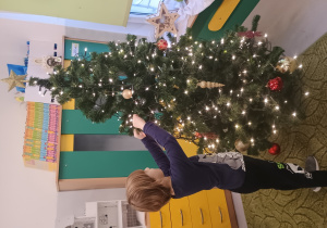 Chłopiec zawiesza ozdobę na choinkę