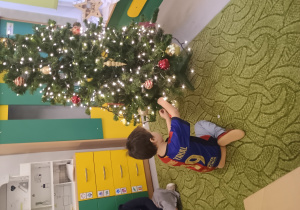 Chłopiec zawiesza ozdobę na choinkę