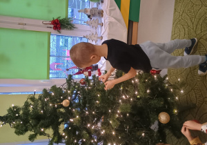 Chłopiec zawiesza ozdobę na choinkę